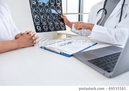 Doctor holding and looking at x-ray film examining Doctor holding and looking at x-ray film examining 69535581