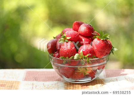 strawberry in bowl close up vertical photo with copy space on green grass background 69538255