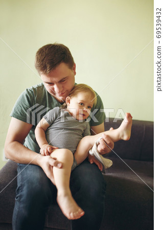 Young handsome father daddy dressing up his cute toddler baby gi 69539432