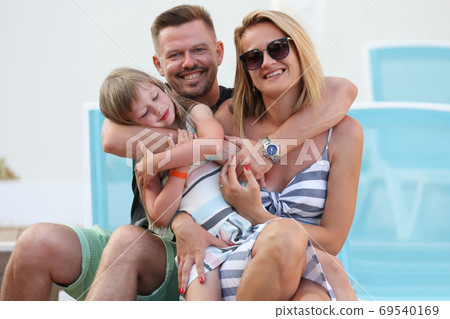 Man, woman and girl hug together. 69540169