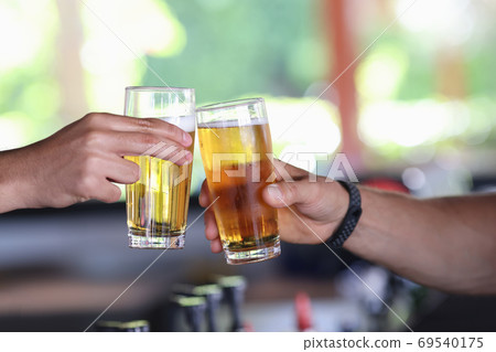 Two male hand hold glass of cold beer and clink glasses. Two male hand hold glass of cold beer and clink glasses. 69540175
