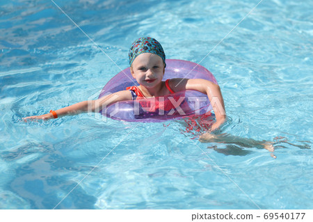 Beautiful girl swim in blue pool with inflatable ring. Beautiful girl swim in blue pool with inflatable ring. 69540177