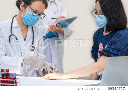 The doctor used a syringe to suck blood from a young woman to ta The doctor used a syringe to suck blood from a young woman to ta 69540737