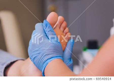 Therapist hands in protective gloves massaging woman's feet. Therapist hands in protective gloves massaging woman's feet. 69540914