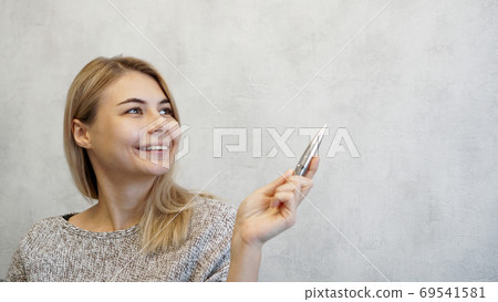 The woman shows with a pen on a gray wall. Place for information 69541581