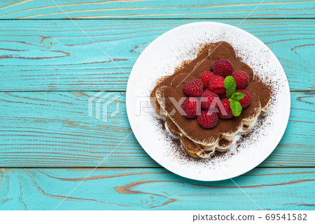 portion of Classic tiramisu dessert with raspberries on blue wooden background portion of Classic tiramisu dessert with raspberries on blue wooden background 69541582