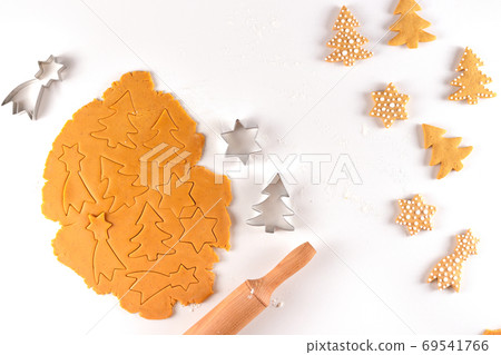 Fragrant dough for gingerbread cookies next to the cookie cutters. Fragrant dough for gingerbread cookies next to the cookie cutters. 69541766