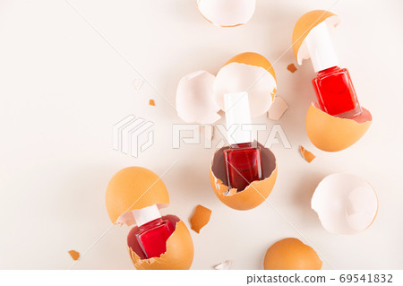 Three red nail polishes in eggshell on light background 69541832