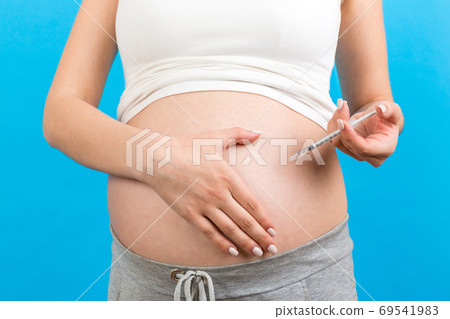 Close up of pregnant woman making injection of insulin in her be Close up of pregnant woman making injection of insulin in her be 69541983