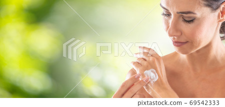 Beautiful woman putting a hydrating lotion on the back fo her ha Beautiful woman putting a hydrating lotion on the back fo her ha 69542333