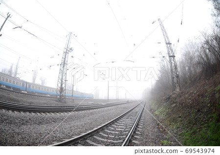 The Ukrainian suburban train rushes along the railway in a misty The Ukrainian suburban train rushes along the railway in a misty 69543974
