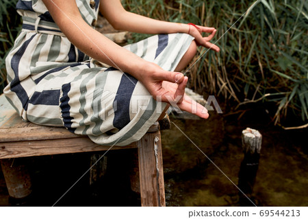 Young woman in dress meditating on the nature 69544213
