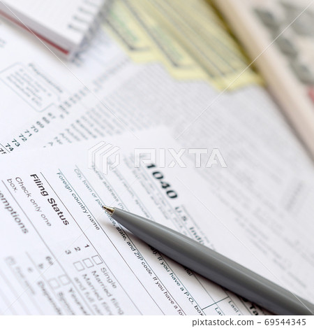 The pen, notebook, calculator, and dollar bills is lies on the t 69544345