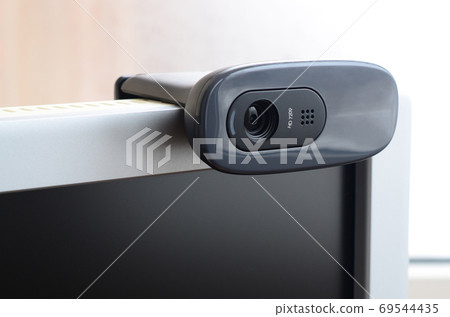 A modern web camera is installed on the body of a flat screen mo 69544435