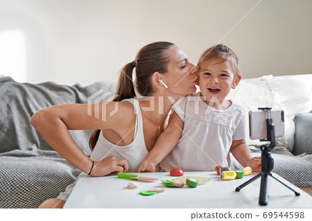 Mother with child streaming online video of unboxing wooden toys. Influencer occupation, mommy blog 69544598
