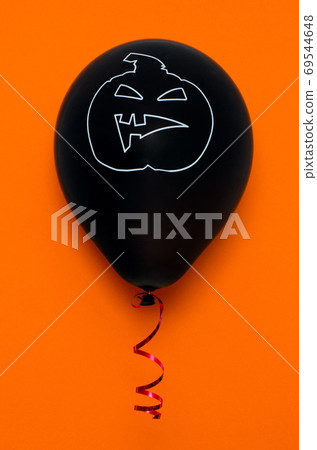 Black balloon on orange background with scary face. Halloween decoration. Black balloon on orange background with scary face. Halloween decoration. 69544648