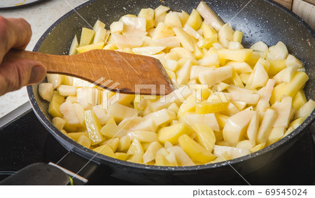 A woman frying potatoes in the kitchen A woman frying potatoes in the kitchen 69545024