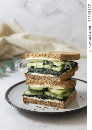 Healthy sandwich with cucumber and kale leaves. Vegan food snack, breakfast. 69545167