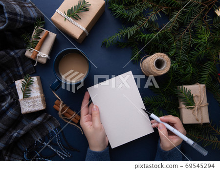 Hands of a girl writing a Christmas list On a blue background Hands of a girl writing a Christmas list On a blue background 69545294