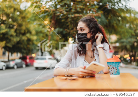 A young woman in a mask from the virus went for coffee. The city is in quarantine. A young woman in a mask from the virus went for coffee. The city is in quarantine. 69546157
