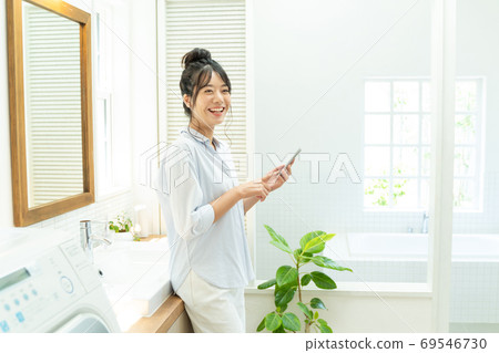 Young woman using a smartphone in the bathroom 69546730