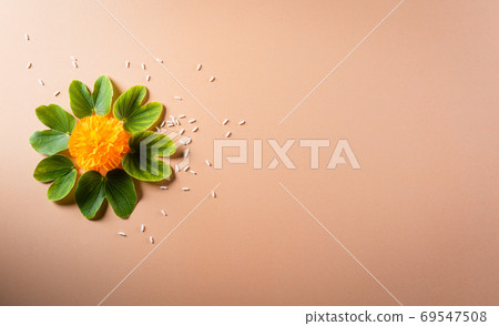 Happy Dussehra. Yellow flowers, green leaf and rice on orange pa 69547508