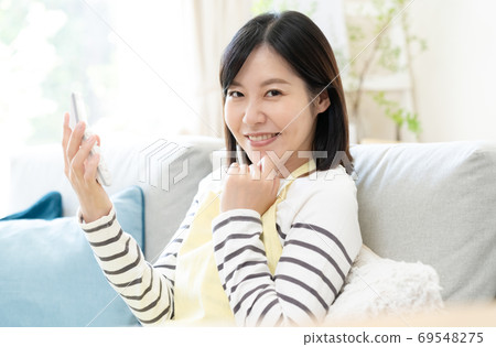 A middle-aged woman looking at a calculator and smiling A middle-aged woman looking at a calculator and smiling 69548275