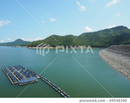 Floating solar panel on the lake with arch dam, mountain background. This technology called FPV or Floating photovoltaic. Clean technology concept and output is renewable energy. 69548390