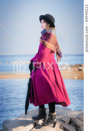Portrait girl in a crimson coat against background of sea 69549222
