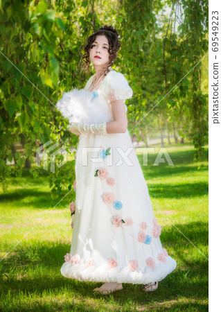 Beautiful woman in a dress of the bride with a fan in park Beautiful woman in a dress of the bride with a fan in park 69549223