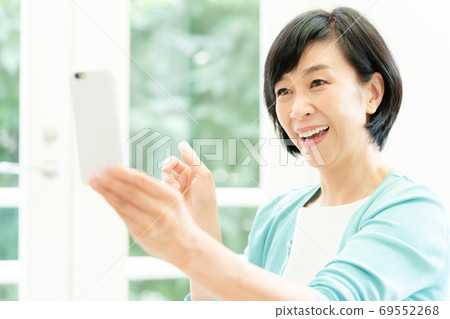 Middle woman making a video call on her smartphone Middle woman making a video call on her smartphone 69552268