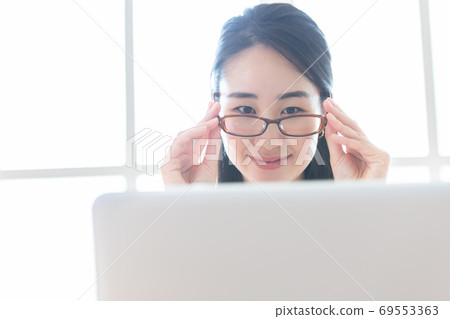 在商務計算機上工作時戴藍色輕便眼鏡的女人 在商務計算機上工作時戴藍色輕便眼鏡的女人 69553363