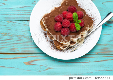 portion of Classic tiramisu dessert with raspberries on blue wooden background portion of Classic tiramisu dessert with raspberries on blue wooden background 69555444