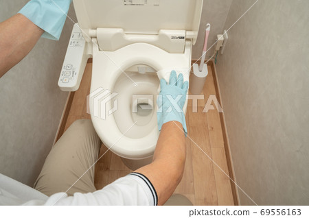 Husband cleans the toilet with a disinfectant sheet Husband cleans the toilet with a disinfectant sheet 69556163