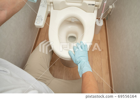 Husband cleans the toilet with a disinfectant sheet Husband cleans the toilet with a disinfectant sheet 69556164