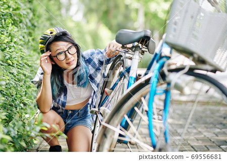 Woman needs to fix bicycle Woman needs to fix bicycle 69556681