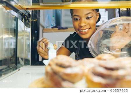 Waitress taking pastry from showcase 69557435