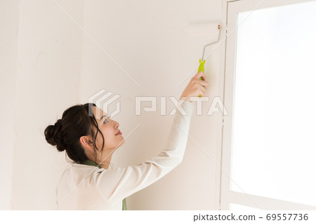 A woman who paints the walls of a house with DIY 69557736
