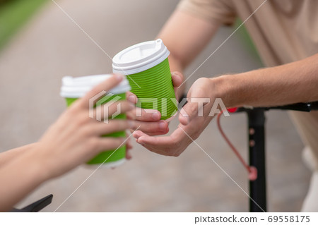 Close up picture of human hands with coffee cups 69558175