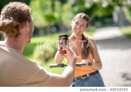 Young man making photo of his smiling girlfriend 69558293