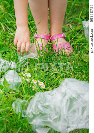 Hand of child cleans green grass from plastic trash 69558735
