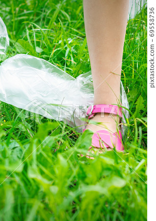 Plastic bags trash with children's feet on green grass 69558736