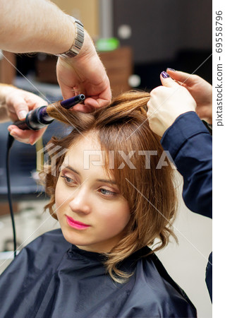 Hairdresser curling long light brown hair Hairdresser curling long light brown hair 69558796