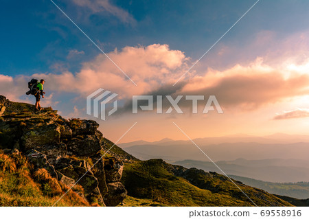 A little boy standing on a large rocky rock admires the landscape of the Carpathians, the top of Mount Pip Ivan Chornohirsky. 69558916
