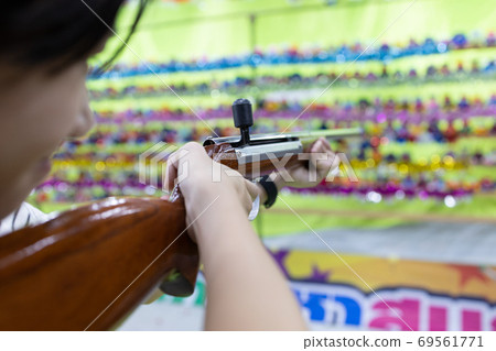 Happy asian child girl holding wooden gun,aim to the point,shooting the target,female playing shooting games for a carnival at night,the annual festival at Christmas,New year winter,Bangkok,Thailand Happy asian child girl holding wooden gun,aim to the point,shooting the target,female playing shooting games for a carnival at night,the annual festival at Christmas,New year winter,Bangkok,Thailand 69561771