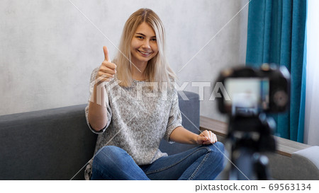 Wwoman or blogger with camera recording video and showing thumbs up Wwoman or blogger with camera recording video and showing thumbs up 69563134