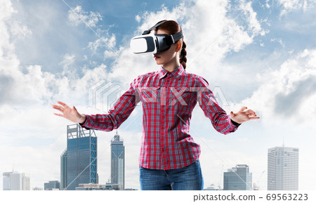 Girl in checked shirt wearing VR glasses experiencing another reality Girl in checked shirt wearing VR glasses experiencing another reality 69563223