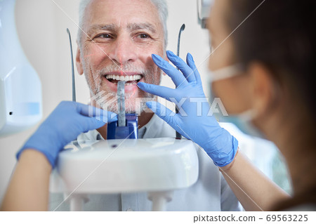 Aged man getting his teeth examined in a panormic x-ray machine Aged man getting his teeth examined in a panormic x-ray machine 69563225