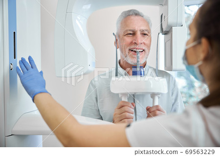 Professional dentist in charge of a panoramic dental x-ray machine Professional dentist in charge of a panoramic dental x-ray machine 69563229