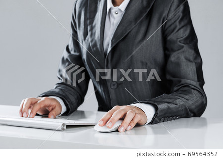 Closeup of businesswoman hand typing on keyboard with mouse on wood table 69564352